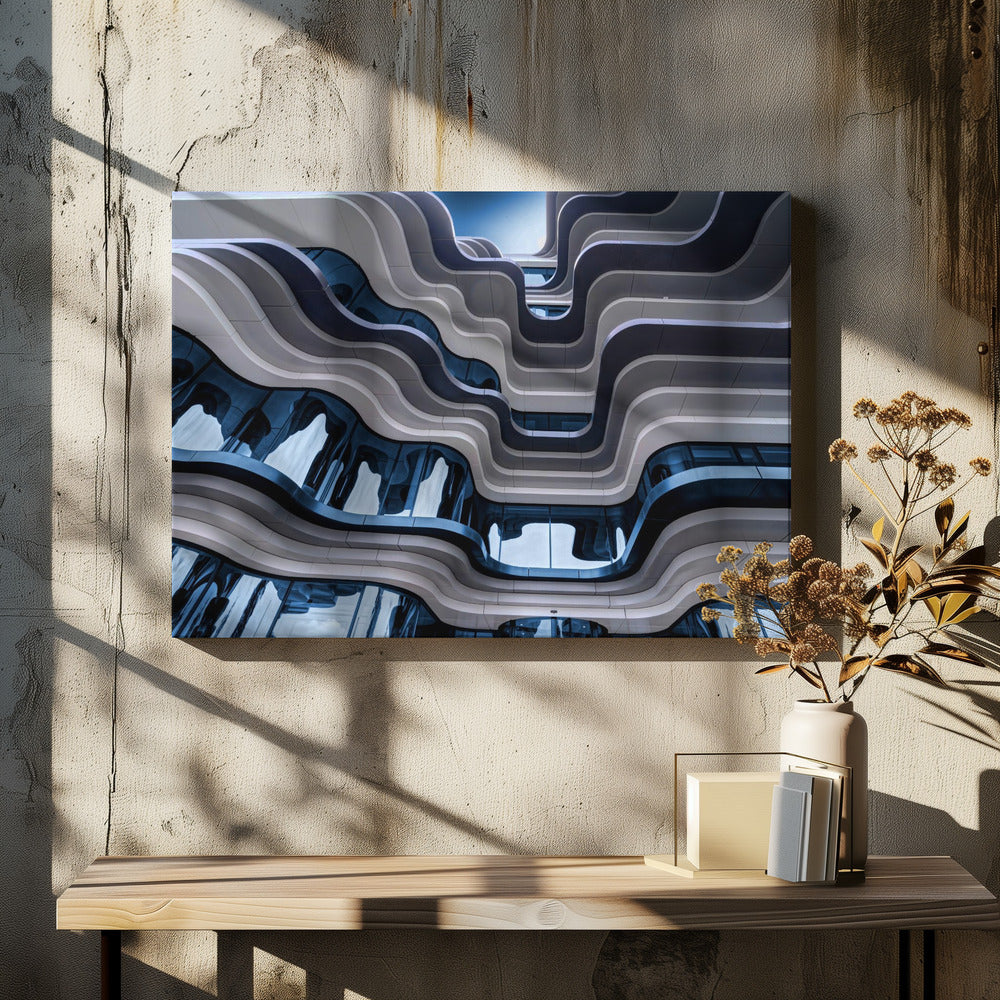 A low-angle view of a modern building with a striking, wavy facade. Alternating bands of light and dark grey create a fluid, ribbon-like pattern, with curved glass windows reflecting the deep blue sky. Artwork