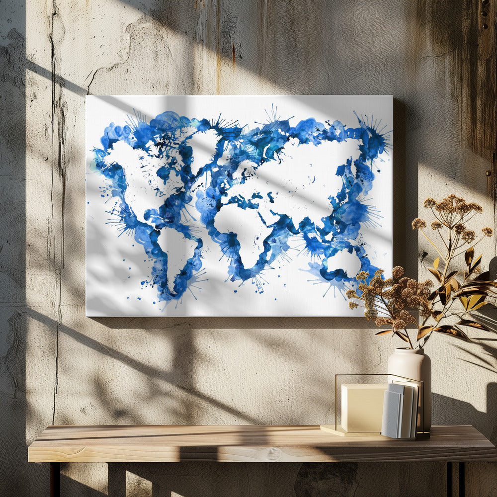 An abstract watercolor world map in a silver frame. The continents are depicted in white negative space, while the oceans are represented by vibrant blue splashes, splatters, and drips of paint on a white background. Artwork