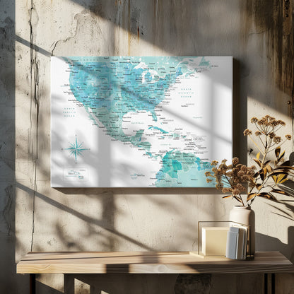 A decorative map of North, Central, and South America in a grey frame. The map has a watercolor texture in shades of blue and teal on a white background, with countries and major cities labeled in a dark font. Print