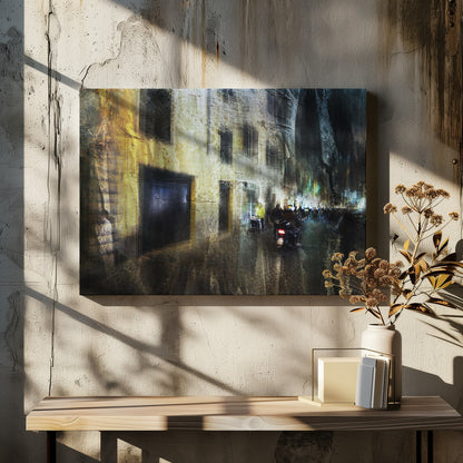 A framed abstract digital artwork depicting a busy, narrow city street at night. The image has a heavily textured, painterly style, with blurred motion effects. A weathered, yellow-lit building is on the left, while the street on the right is filled with indistinct figures of people and a motorcycle, with city lights glowing in the distance. Wall Art