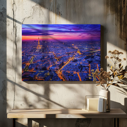 An aerial panoramic view of Paris at dusk, with the cityscape illuminated in cool blue and warm yellow lights. The Eiffel Tower is prominently lit on the left under a dramatic sunset sky transitioning from orange and pink to deep purple. Poster
