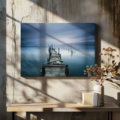 A framed, long exposure photograph of a weathered wooden pier extending into calm, misty blue water under a dramatic, cloudy sky. Wall Art