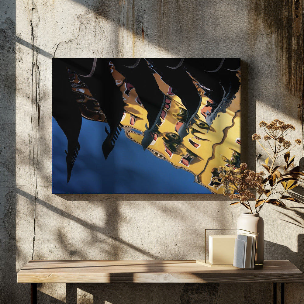 An abstract photograph of a distorted reflection in water, showing a vibrant yellow building against a deep blue sky, with the dark silhouettes of several Venetian gondola prows cutting across the top of the image. The entire scene is enclosed in a silver picture frame. Print