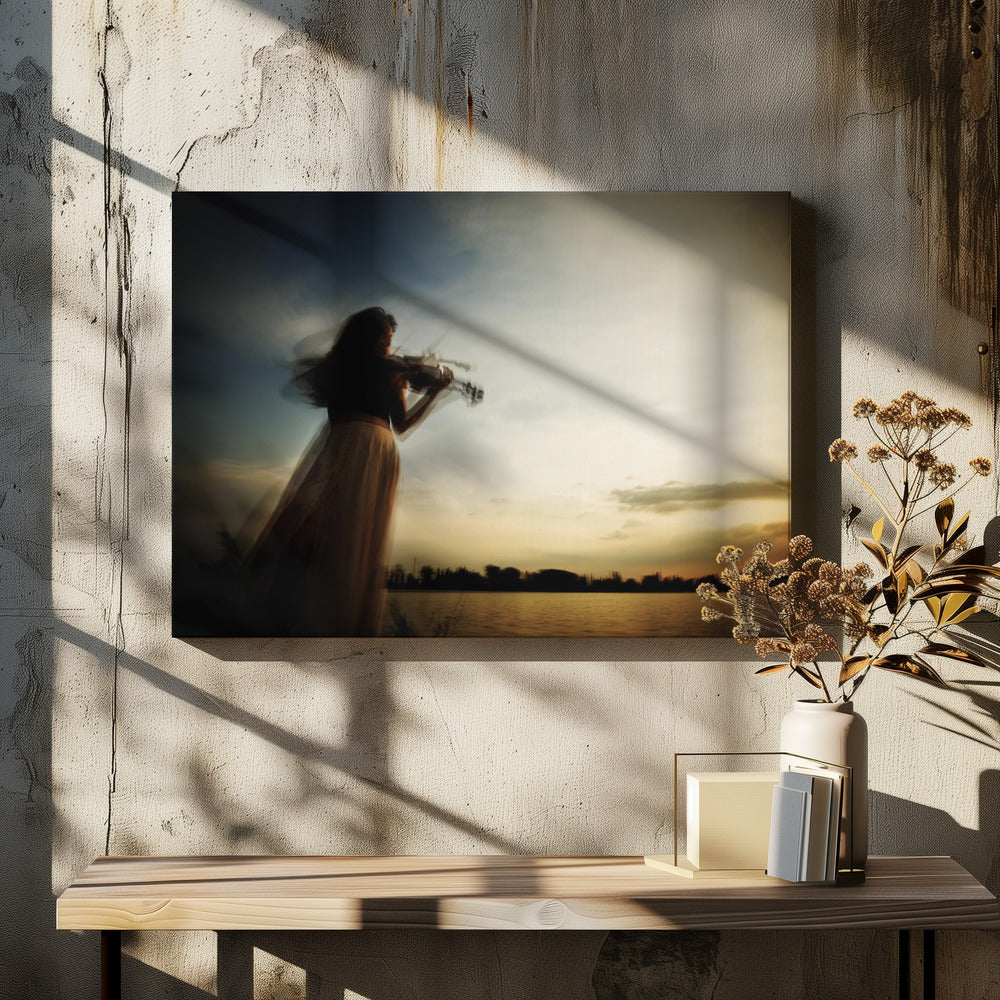 An artistic, framed photograph with motion blur capturing the silhouette of a woman in a long flowing skirt playing the violin by a lake against a dramatic sunset sky. Poster