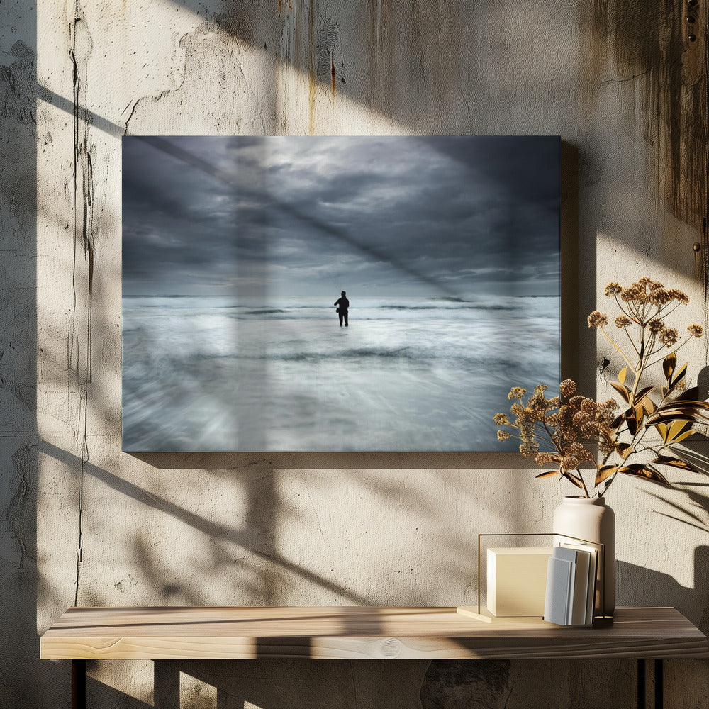 A moody, long-exposure photograph of a silhouetted fisherman standing in the churning white surf of the ocean under a dark, stormy sky, presented in a silver frame. Wall Art