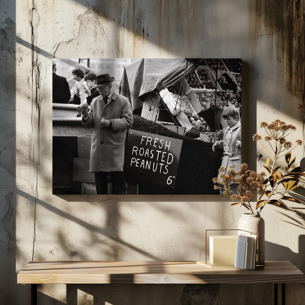 A vintage black and white photograph of an elderly man in a fedora and overcoat feeding a pigeon from his hand at an outdoor market. A sign for 'FRESH ROASTED PEANUTS' is visible next to him, and a young boy in a coat watches nearby. Wall Art