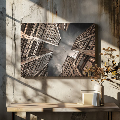 A dramatic, low-angle photograph looking up at the sky between several tall, sepia-toned skyscrapers that converge towards the center. Two birds are seen flying in the moody, dark grey sky. The image has a vintage feel and is presented in a silver frame. Wall Art