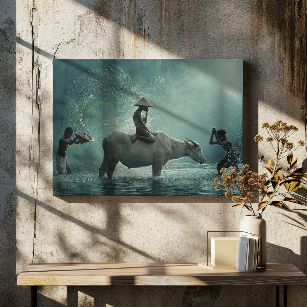 A serene photograph of three young boys playing in a river with a large water buffalo, one boy sits atop the animal while the others splash water, all set against a misty green backdrop and framed in silver. Print