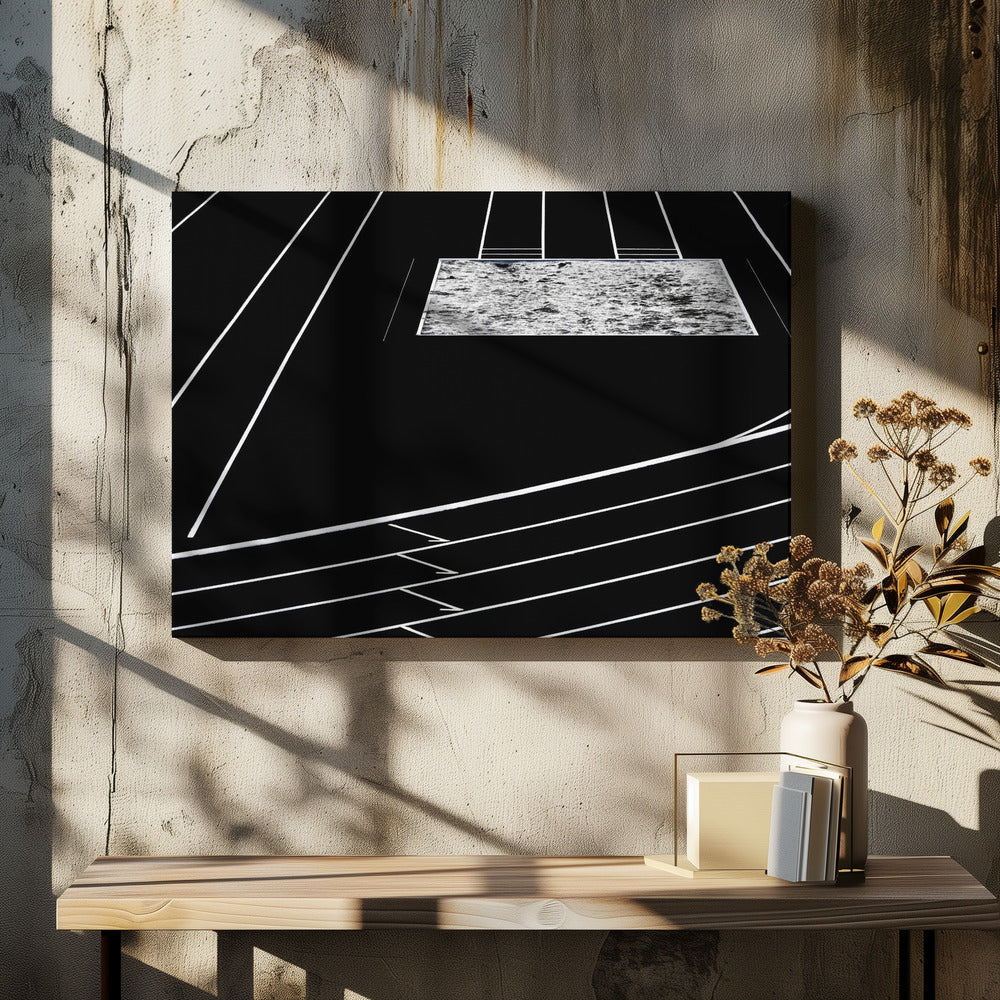 A high-contrast, black and white abstract artwork depicting a running track from an elevated perspective. Stark white lines representing lanes curve across a solid black background. In the upper portion, a rectangular shape filled with a textured, water-like pattern replaces a typical sand pit. The entire piece is presented within a silver frame. Print