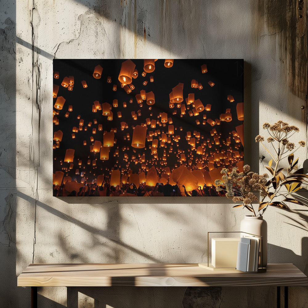 A framed photograph of a sky lantern festival at night, with hundreds of warm, orange-glowing lanterns floating up into the pitch-black sky from a crowd of people below. Artwork