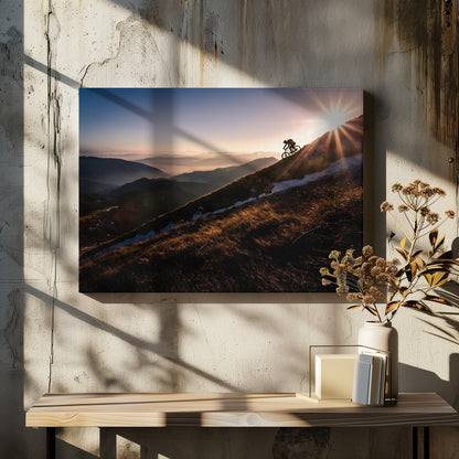 A silhouette of a mountain biker pushing their bike up a steep mountainside against a brilliant sunrise. The sun is cresting the peak, creating a starburst effect with long light rays. In the background, layers of mountains and valleys are filled with a soft morning mist under a clear gradient sky. Artwork