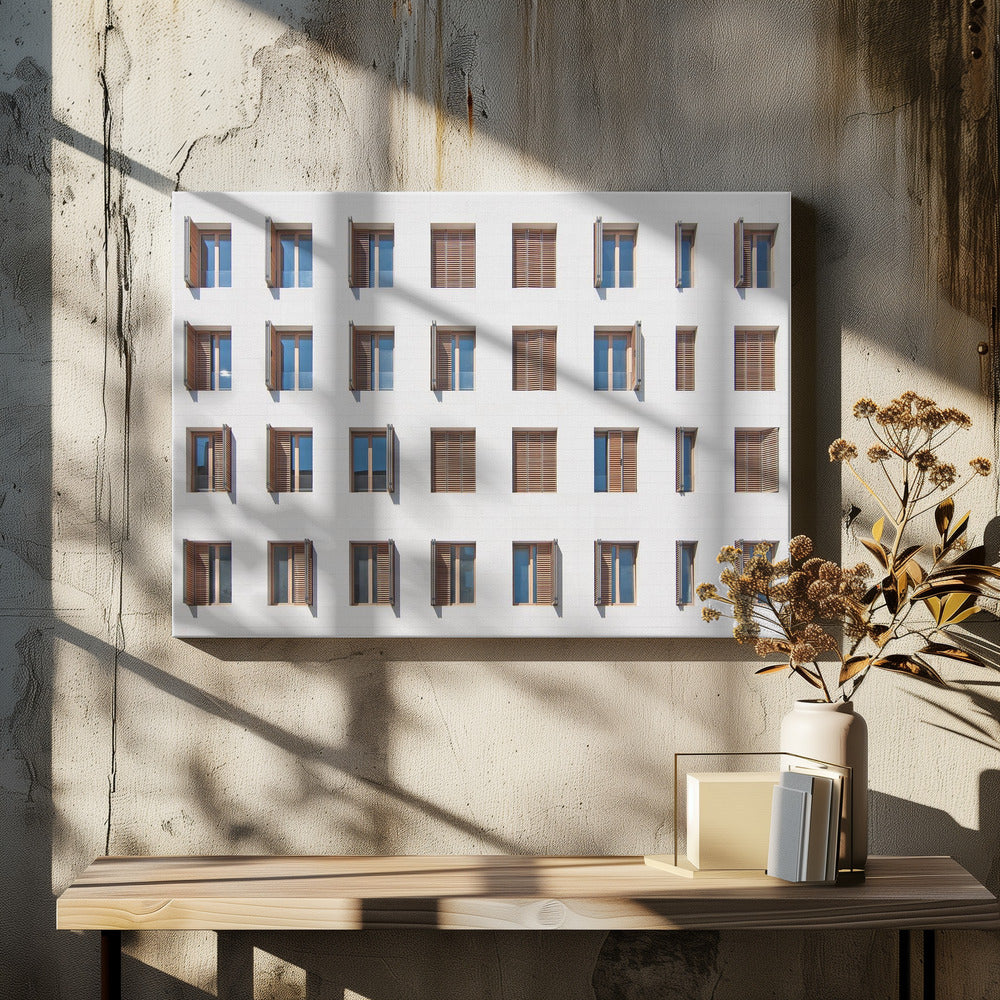 A symmetrical architectural photo of a modern white building facade featuring a grid of twenty-eight windows with wooden louvered shutters, some open and some closed, creating a varied pattern, all within a brushed silver frame. Decor