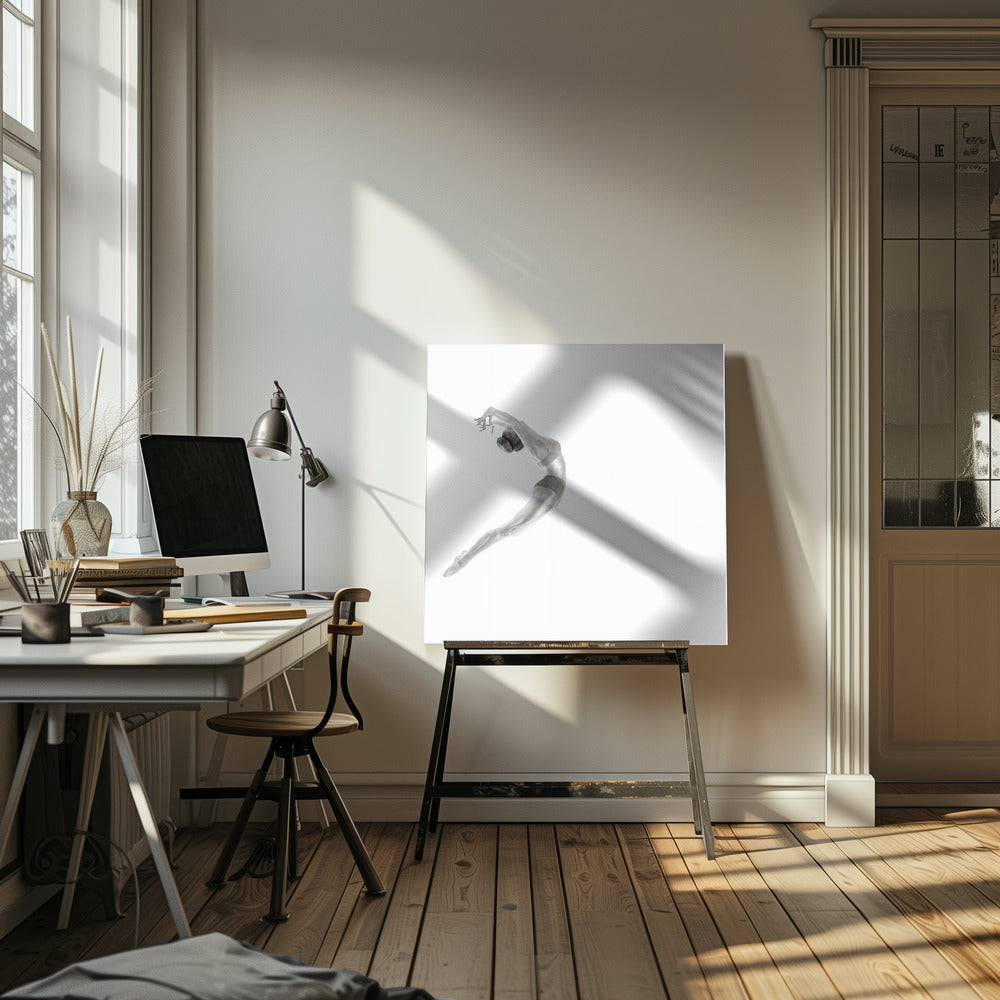 A minimalist black and white photograph of a graceful dancer frozen in mid-air, her body arched backward in an elegant C-shape against a stark white background. The artwork is presented in a light wood frame. Decor