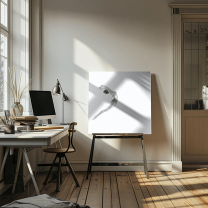 A minimalist black and white photograph of a graceful dancer frozen in mid-air, her body arched backward in an elegant C-shape against a stark white background. The artwork is presented in a light wood frame. Decor
