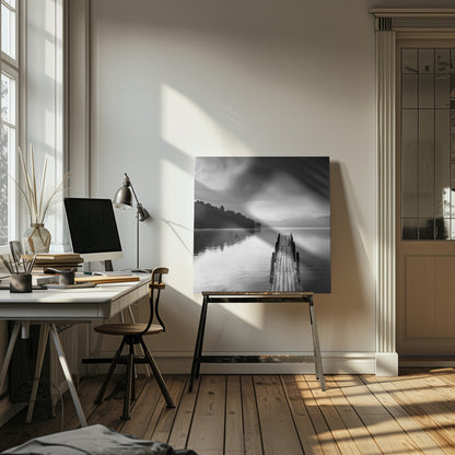A framed, moody black and white photograph of a wooden pier extending into a calm lake under a cloudy sky, with a forested shoreline and distant mountains in the background. Poster