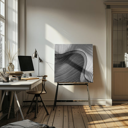 A square, black and white abstract photograph in a light wood frame. The image features layers of flowing, curved surfaces with parallel grooves, creating a strong sense of texture and depth. Lighter, striped layers with vertical lines curve over a darker, undulating section, resembling waves or sculpted wood, drawing the eye into a central dark crevice. Decor