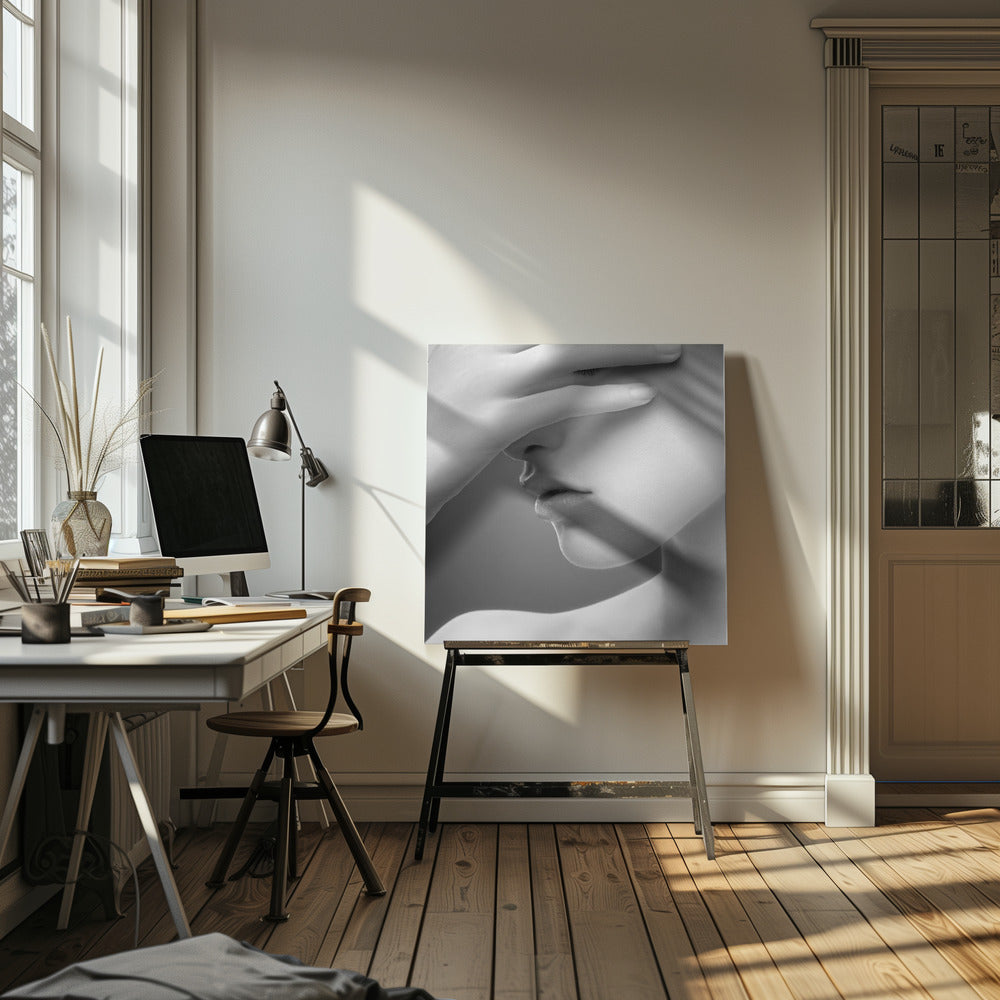A close-up, black and white photograph of a woman's face. Her hand covers her eyes, revealing only the lower half of her face including her nose, lips, and chin. The image has a soft, sensual quality and is set within a light-colored wooden frame. Decor