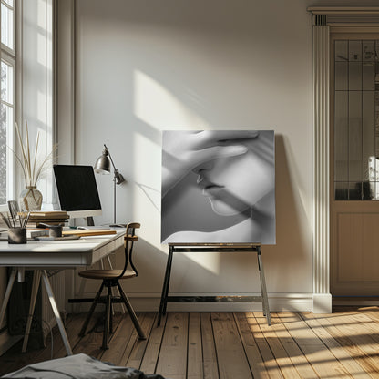 A close-up, black and white photograph of a woman's face. Her hand covers her eyes, revealing only the lower half of her face including her nose, lips, and chin. The image has a soft, sensual quality and is set within a light-colored wooden frame. Decor
