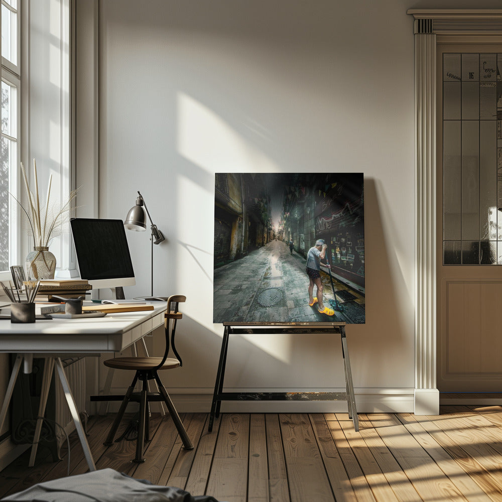 A wide-angle, atmospheric photograph of a man in bright yellow clogs mopping a wet, narrow cobblestone alley. The dark, gritty city street is lined with old buildings and closed storefronts, with another person walking in the distant light at the end of the alley. Wall Art