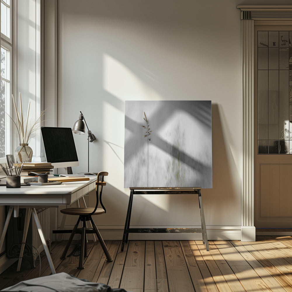 A minimalist photograph in a light wood frame featuring a single, delicate stalk of wild grass in sharp focus against a soft, vertically blurred background of gray and muted green tones, creating a tranquil and artistic impression. Print