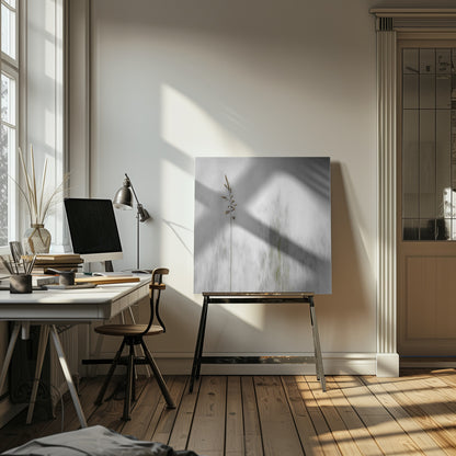A minimalist photograph in a light wood frame featuring a single, delicate stalk of wild grass in sharp focus against a soft, vertically blurred background of gray and muted green tones, creating a tranquil and artistic impression. Print