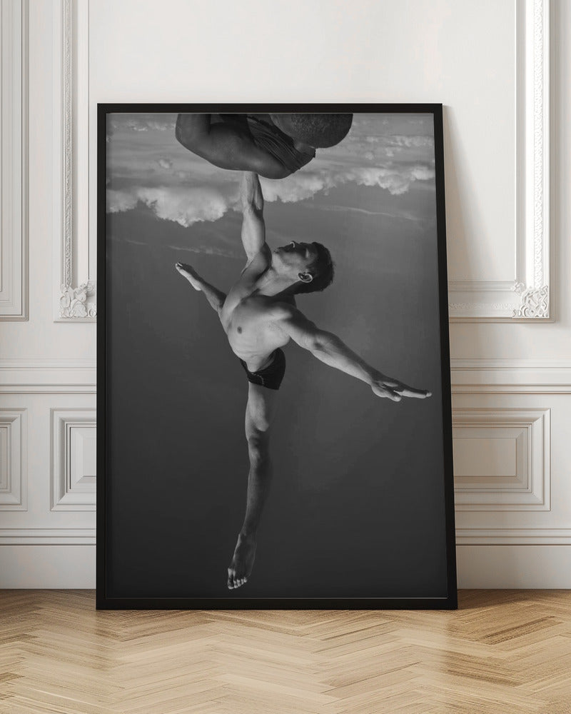 A surreal black and white photograph of two male acrobats. One man, in a graceful dance-like pose balancing on one leg, holds another man aloft with a single outstretched arm. The man being held is upside down against a backdrop of clouds, creating a gravity-defying and artistic illusion. Print