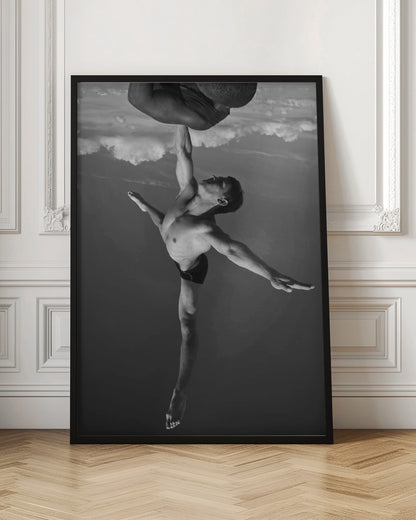 A surreal black and white photograph of two male acrobats. One man, in a graceful dance-like pose balancing on one leg, holds another man aloft with a single outstretched arm. The man being held is upside down against a backdrop of clouds, creating a gravity-defying and artistic illusion. Print