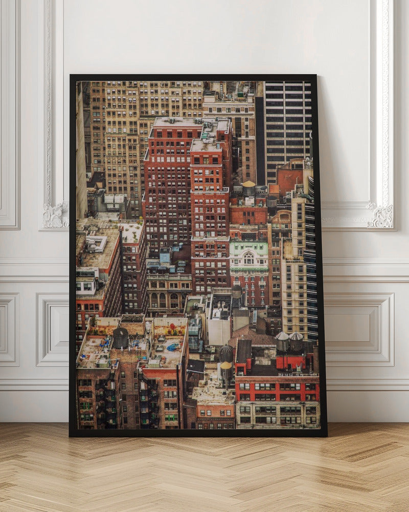 A high-angle, telephoto view of a dense cluster of New York City buildings, featuring a mix of red and brown brick architecture, with numerous windows creating a geometric pattern and several classic wooden water towers perched on the rooftops. Print
