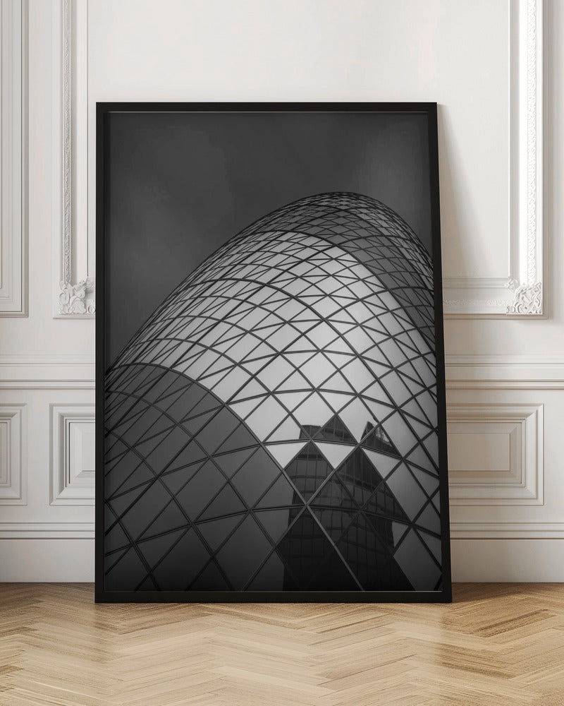 A framed, low-angle, black and white photograph of the curved, glass-paneled facade of a modern skyscraper, creating a dynamic pattern of reflective diamonds against a dark, moody sky. Artwork