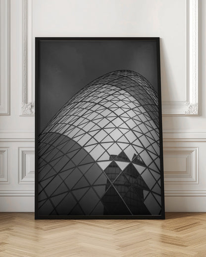 A framed, low-angle, black and white photograph of the curved, glass-paneled facade of a modern skyscraper, creating a dynamic pattern of reflective diamonds against a dark, moody sky. Artwork