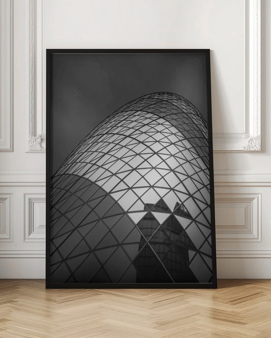 A framed, low-angle, black and white photograph of the curved, glass-paneled facade of a modern skyscraper, creating a dynamic pattern of reflective diamonds against a dark, moody sky. Artwork