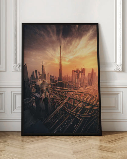 A dramatic high-angle photograph of the Dubai skyline at sunset. The Burj Khalifa stands tall in the center, bathed in the warm light of the setting sun, while a complex network of highways and interchanges weaves between modern skyscrapers in the foreground under a cloudy, orange-tinted sky. Poster