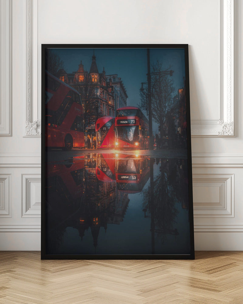 A moody, low-angle photograph of a wet London street at dusk, with a vibrant red double-decker bus reflected perfectly in a large puddle in the foreground. Print