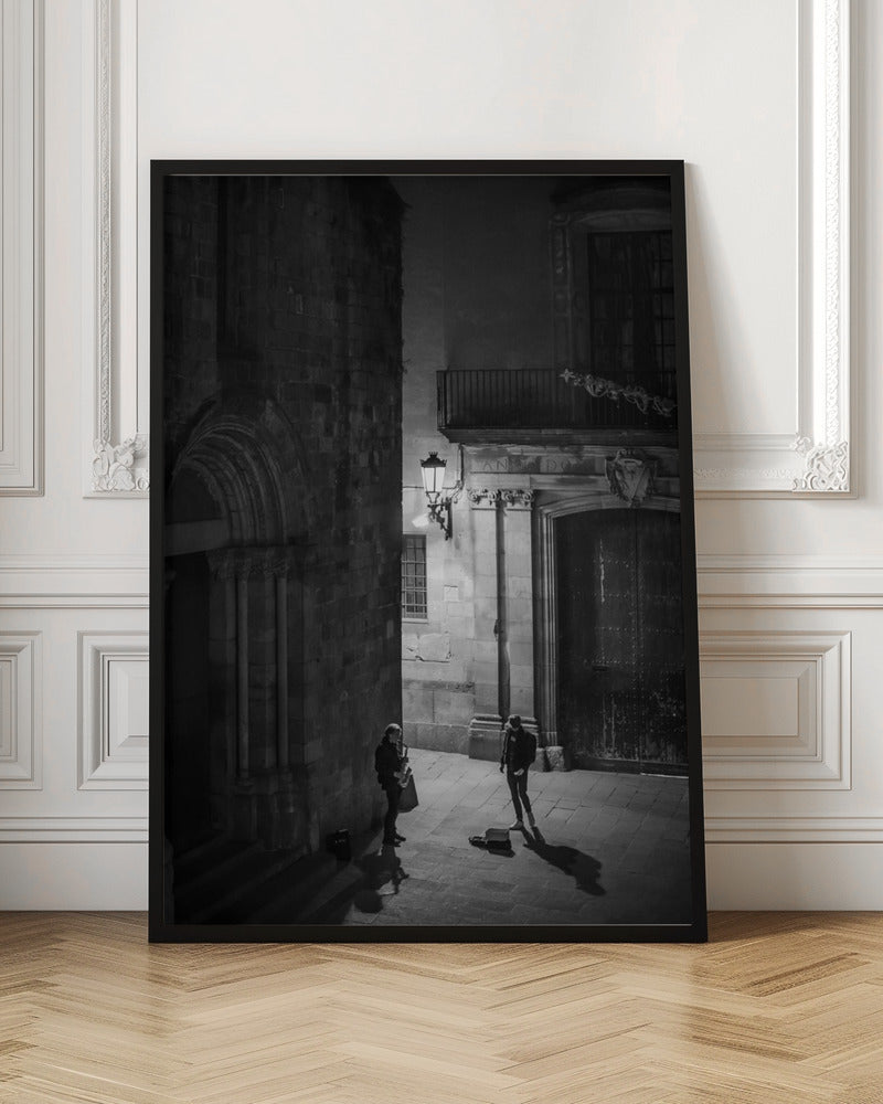 A high-angle, black and white photograph of a street musician playing a saxophone for a lone listener in a narrow stone alley at night. The scene is illuminated by an ornate streetlamp, casting long shadows on the cobblestone ground. Wall Art
