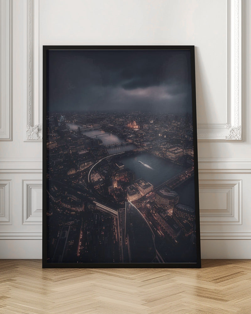 An aerial photograph of London at night from a high vantage point, overlooking the winding River Thames illuminated by the golden glow of city lights under a dark, dramatic, and cloudy sky. Wall Art