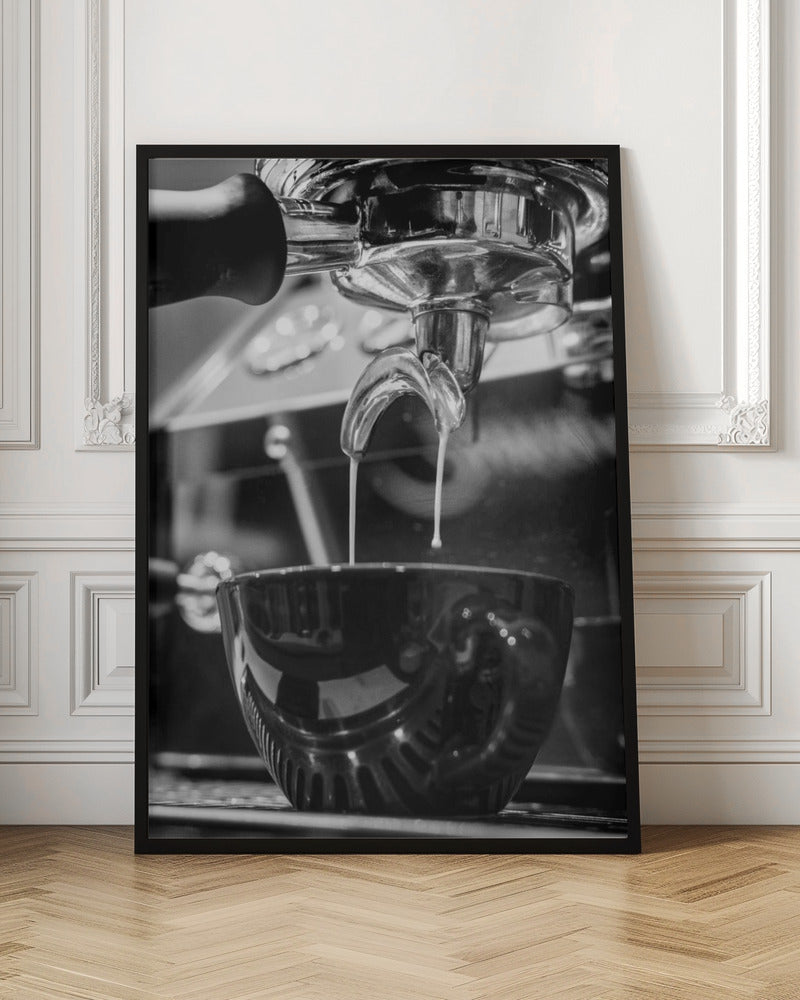 A close-up, black and white photograph of an espresso machine pouring two streams of fresh coffee from a chrome portafilter into a dark, glossy cup. Print