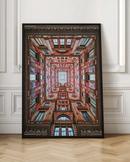 A symmetrical, worm's-eye view looking up through the center of an ornate, multi-story courtyard. The red and gold walls are covered in intricate details and frescoes, receding into the distance towards a square glass skylight. The entire artwork is presented within a decorative dark brown frame. Artwork