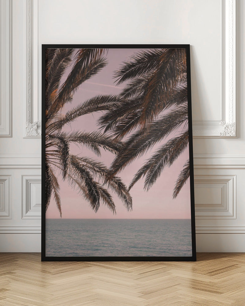 Dark palm tree fronds hang over a calm teal ocean under a soft pink sky, creating a serene and tropical atmosphere. The view is from under the palm tree looking out towards the water. Artwork