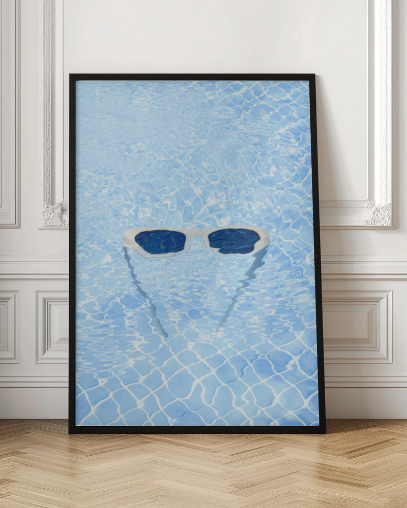 A pair of white-framed sunglasses with dark lenses floats on the surface of a bright blue swimming pool. The rippling water distorts the view of the tiled pool floor, and the sunglasses cast a faint shadow underneath. Print