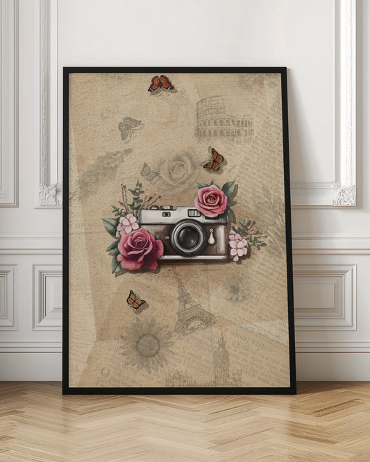 A vintage-style collage art piece in a black frame. The central focus is a retro camera adorned with pink and magenta roses and green leaves. The background is a sepia-toned collage of old newspaper or book pages, with faint illustrations of European landmarks like the Colosseum and the Eiffel Tower, along with butterflies and flowers. Poster