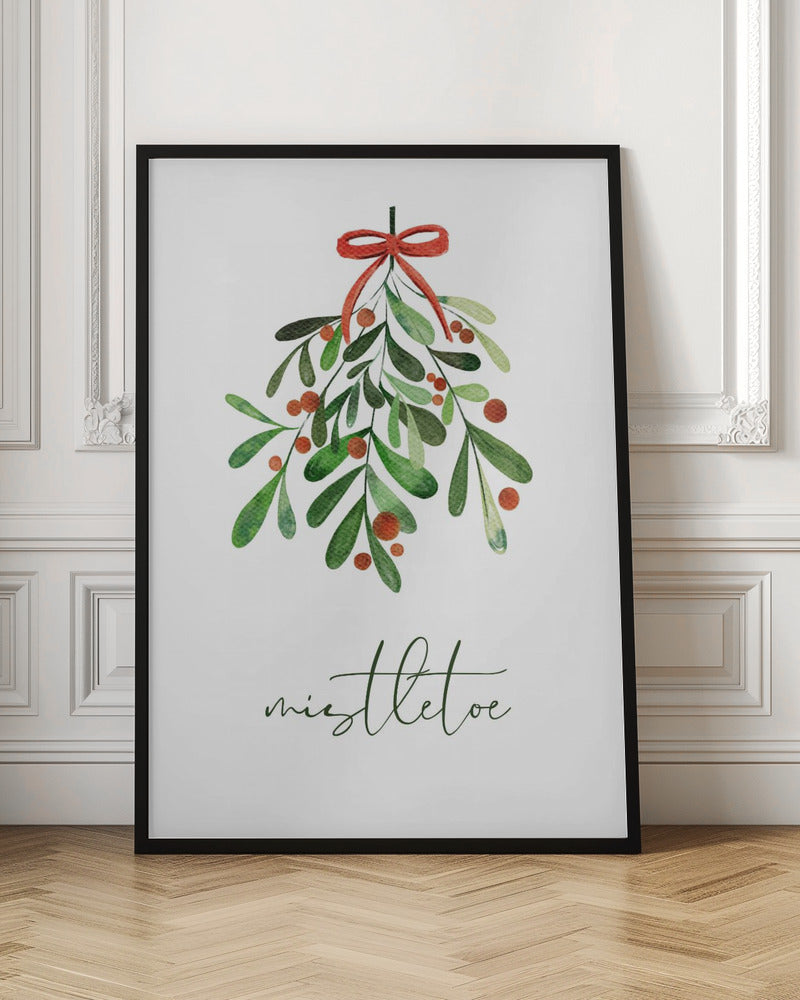 A framed watercolor illustration of a sprig of mistletoe with green leaves and red berries, tied with a red bow. Below the plant, the word 'mistletoe' is written in a cursive script on a clean white background. Artwork