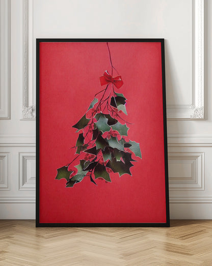 A festive illustration of a bunch of green holly with red berries hanging upside down, tied with a small red bow. The artwork is set against a solid, bright red background and enclosed in a thin black frame. Print