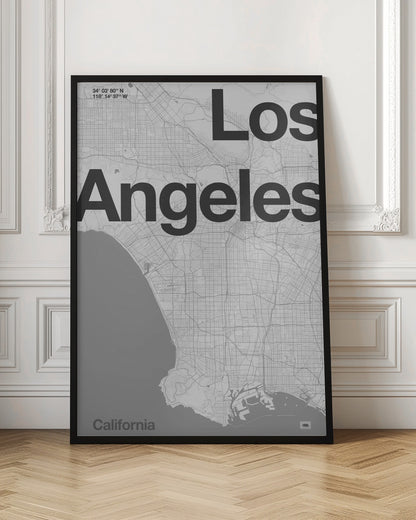 A minimalist black and white framed map of Los Angeles. The poster features a detailed street grid of the city and its coastline. The words 'Los Angeles' are overlaid in a large, bold, black sans-serif font. In the top-left corner are the coordinates, and in the bottom-left is the word 'California'. Decor