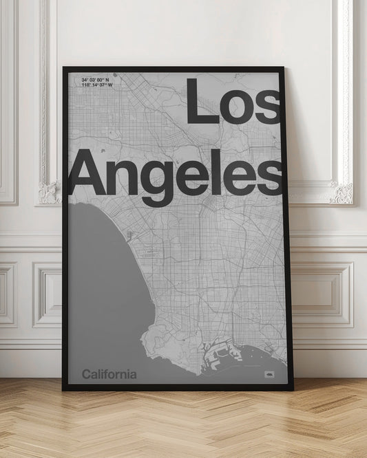 A minimalist black and white framed map of Los Angeles. The poster features a detailed street grid of the city and its coastline. The words 'Los Angeles' are overlaid in a large, bold, black sans-serif font. In the top-left corner are the coordinates, and in the bottom-left is the word 'California'. Decor