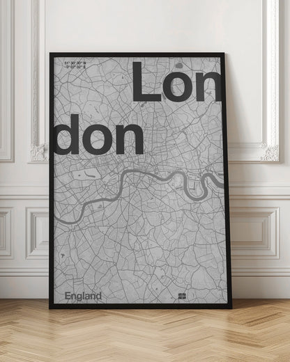 A framed, minimalist black and white street map of London. The word 'London' is split into two lines, 'Lon' and 'don', in large, bold black font overlaid on the light grey map. The River Thames snakes through the center in a darker grey, matching the intricate street grid. Coordinates are in the top left corner, and 'England' is in the bottom left. Decor