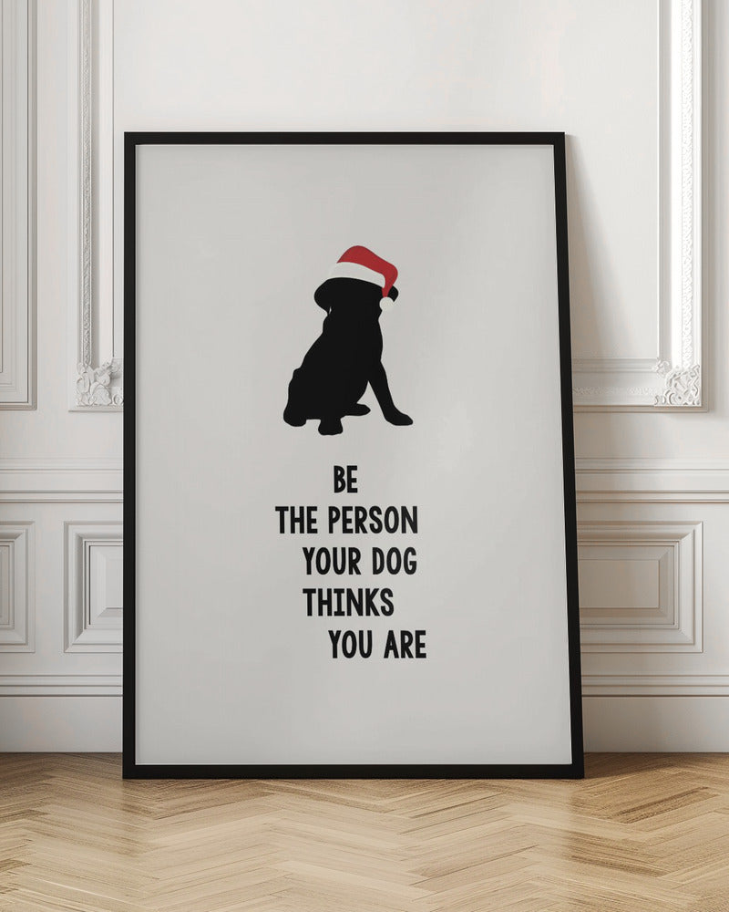 A framed art print featuring a black silhouette of a dog wearing a red Santa hat on an off-white background. Below the dog is the motivational quote, 'BE THE PERSON YOUR DOG THINKS YOU ARE' in black block letters. Decor