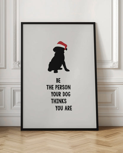 A framed art print featuring a black silhouette of a dog wearing a red Santa hat on an off-white background. Below the dog is the motivational quote, 'BE THE PERSON YOUR DOG THINKS YOU ARE' in black block letters. Decor