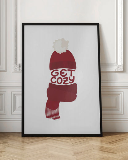 A minimalist illustration of a red knit beanie with a white pom-pom and a matching red scarf. The words 'GET COZY' are written in a playful font, forming the middle section of the hat and scarf against a plain white background, enclosed in a black frame. Poster