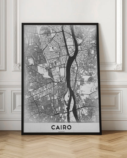 A minimalist black and white framed poster of a street map of Cairo. The Nile River flows vertically through the center of the detailed city grid. The word 'CAIRO' is printed in a bold, black, sans-serif font at the bottom. Decor
