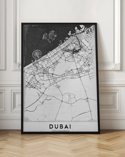 A minimalist black and white map of Dubai in a black frame. The water is depicted in black with a subtle texture, while the land is white, showing the city's road network in thin black lines. Key features like the Palm Jumeirah and The World Islands are visible off the coast. The word 'DUBAI' is written in a bold, black, sans-serif font at the bottom. Decor